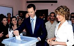 In this photo released on the official Facebook page of the Syrian Presidency, Syrian President Bashar Assad, center, casts his vote as Syrian first lady Asma Assad, right, stands next to him at a polling station, in Damascus, Syria, Tuesday, June 3, 2014. (photo credit: AP/Syrian Presidency via Facebook)