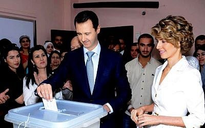 In this photo released on the official Facebook page of the Syrian Presidency, Syrian President Bashar Assad, center, casts his vote as Syrian first lady Asma Assad, right, stands next to him at a polling station, in Damascus, Syria, Tuesday, June 3, 2014. (photo credit: AP/Syrian Presidency via Facebook)