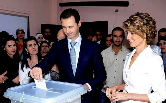 In this photo released on the official Facebook page of the Syrian Presidency, Syrian President Bashar Assad, center, casts his vote as Syrian first lady Asma Assad, right, stands next to him at a polling station, in Damascus, Syria, Tuesday, June 3, 2014. (photo credit: AP/Syrian Presidency via Facebook) In this photo released on the official Facebook page of the Syrian Presidency, Syrian President Bashar Assad, center, casts his vote as Syrian first lady Asma Assad, right, stands next to him at a polling station, in Damascus, Syria, Tuesday, June 3, 2014. (photo credit: AP/Syrian Presidency via Facebook)