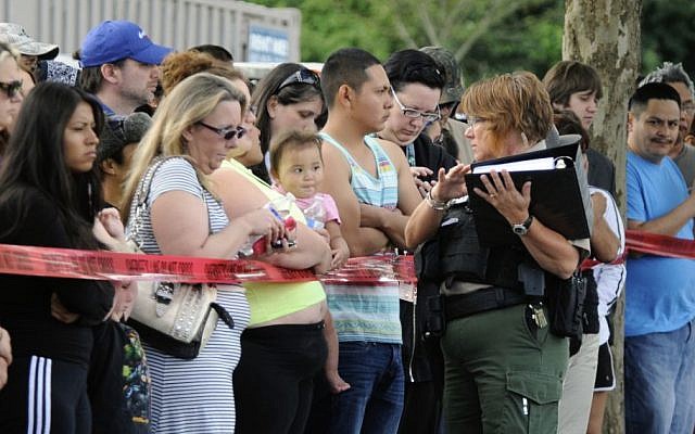 A police officer explains to parents how they are to be reunited as students arrive by bus at a shopping center parking lot in Wood Village, Ore., after a shooting at Reynolds High School Tuesday, June 10, 2014, in nearby Troutdale. (photo credit: AP/Greg Wahl-Stephens) A police officer explains to parents how they are to be reunited as students arrive by bus at a shopping center parking lot in Wood Village, Ore., after a shooting at Reynolds High School Tuesday, June 10, 2014, in nearby Troutdale. (photo credit: AP/Greg Wahl-Stephens)
