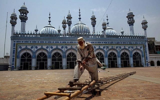 A painter fixes a ladder to whitewash the outer wall of a mosque in preparation for upcoming Islamic holy month of Ramadan in Rawalpindi, Pakistan, Saturday, July 28, 2014. (photo credit: AP/Anjum Naveed)