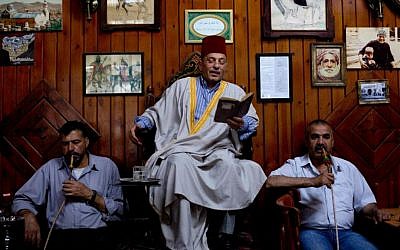 Patrons listen to Ahmad Laham, a professional storyteller, as he reads passages from a book in the al-Nofara café in Damascus, Syria. (photo credit: AP Photo/Dusan Vranic)