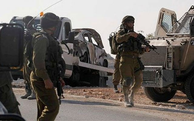 Israeli soldiers transport a burnt car which may have been connected to the disappearance of three teenagers near the West Bank city of Hebron, Friday, June 13, 2014 (photo credit: AP/Nasser Shiyoukhi)
