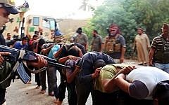 This image posted on a militant website on Saturday, June 14, 2014, which has been verified and is consistent with other AP reporting, appears to show Islamic State militants leading away captured Iraqi soldiers dressed in plain clothes after taking over a base in Tikrit, Iraq. (Photo credit: AP Photo via militant website)