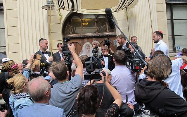 Friends, family, the public and media crowd in in front of the chuppah at the wedding in Wroclaw, Poland, of Katka Reszke and Slawomir Grunberg outside the city's White Stork synagogue, June 22, 2014. (Ruth Ellen Gruber/JTA)