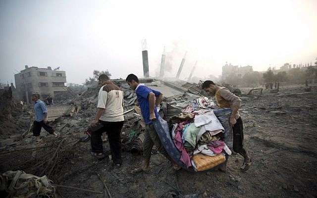 Palestinians collect their belongings from damaged houses after an Israeli missile strike hits Gaza City on July 8, 2014 (photo credit: AFP/MAHMUD HAMS)