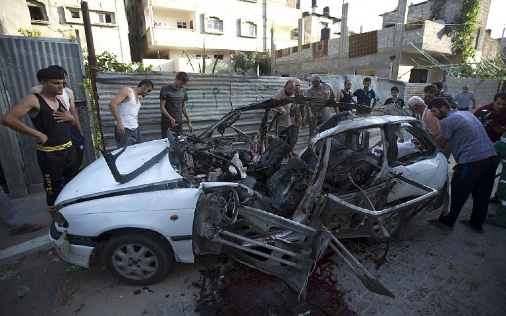 Palestinians inspect the wreckage of a car hit by an Israeli air strike in Gaza City, killing three Islamic Jihad men,according to the IDF, on July 10, 2014. (photo credit: AFP/ MAHMUD HAMS)