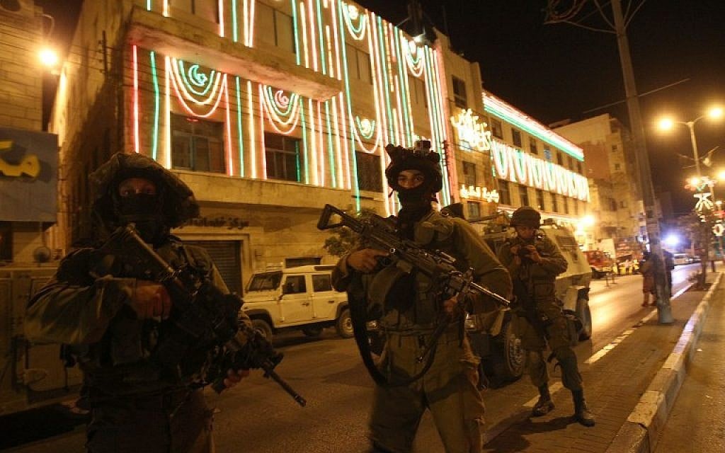 Israeli soldier patrol the streets in the West Bank city of Hebron early Wednesday, on July 2, 2014 (photo credit: AFP/HAZEM BADER)