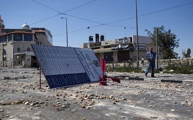 A man walks on a street covered with stones on July 3, 2014, in Jerusalem following clashes between Palestinians and Israeli security forces near the house of a slain Palestinian youth. (photo credit: Ahmad Gharabli/AFP)