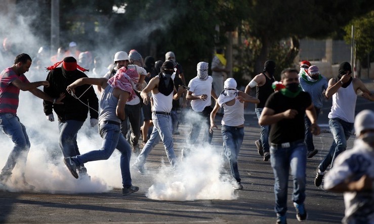 Palestinian protesters stand amid smoke after Israeli forces fired tear gas during clashes in Shuafat, East Jerusalem on July 4, 2014. (Photo credit: AFP/ THOMAS COEX) Palestinian protesters stand amid smoke after Israeli forces fired tear gas during clashes in Shuafat, East Jerusalem on July 4, 2014. (Photo credit: AFP/ THOMAS COEX)