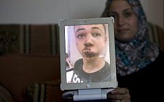 The mother of Tariq Abu Khdeir (portrait), the 15-year-old cousin of the murdered Palestinian youth Mohammed, shows a picture of her son that she took at the hospital after he was allegedly beaten by Israeli border police in East Jerusalem on July 5, 2014 (photo credit: AFP/Ahmad Gharabli)