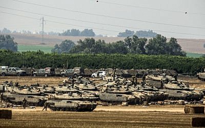 Israeli soldiers stand next to Merkava tanks positioned on the Israeli side of the border with the Gaza Strip on July 7, 2014. ( photo credit: AFP/JACK GUEZ)