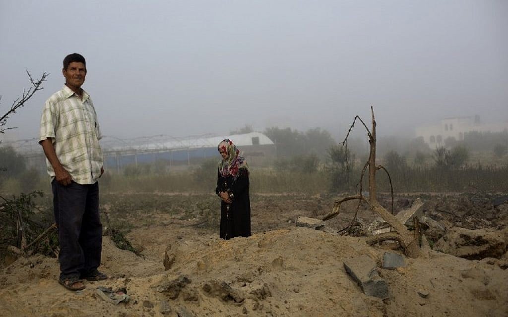 A Palestinian man and a woman inspect the site of an Israeli military strike in Khan Yunis, in the southern Gaza Strip, on July 08, 2014 (photo credit: AFP/MOHAMMED ABED)