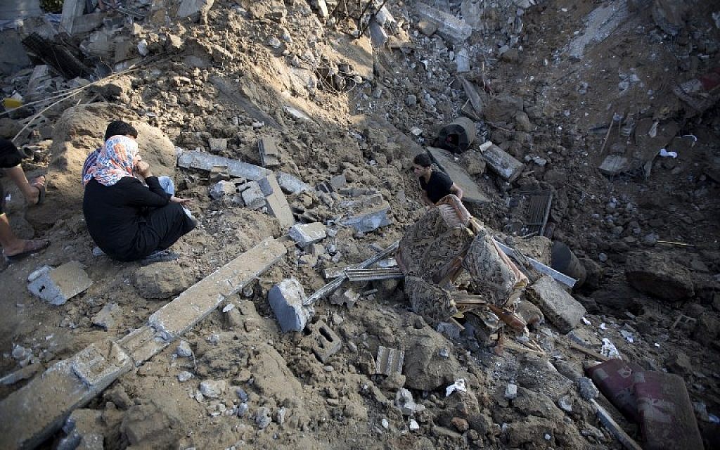 A Palestinian man removes a piece of furniture from the rubble of a home which police said was destroyed in an Israeli air strike in Beit Hanoun, in the northern of Gaza Strip on July 9 2014.  (photo credit: AFP/MOHAMMED ABED)