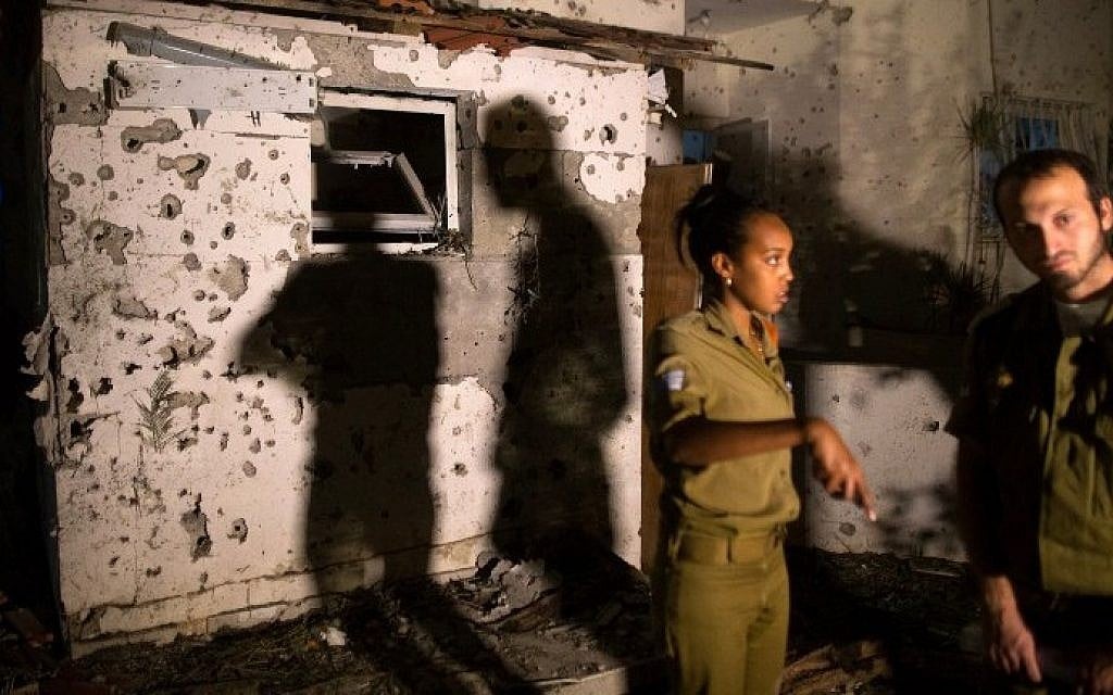Israeli soldiers inspect the damage caused to a house in the southern Israeli city of Beersheba after it was hit by a rocket fired from the Gaza Strip on Thursday, July 10, 2014. (photo credit: Menahem Kahana/AFP)