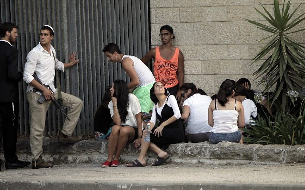Israelis take cover in Jerusalem on July 12, 2014, during a rocket attack by Palestinian militants from the Gaza Strip. (photo credit: AFP/Ahmad Gharabli)