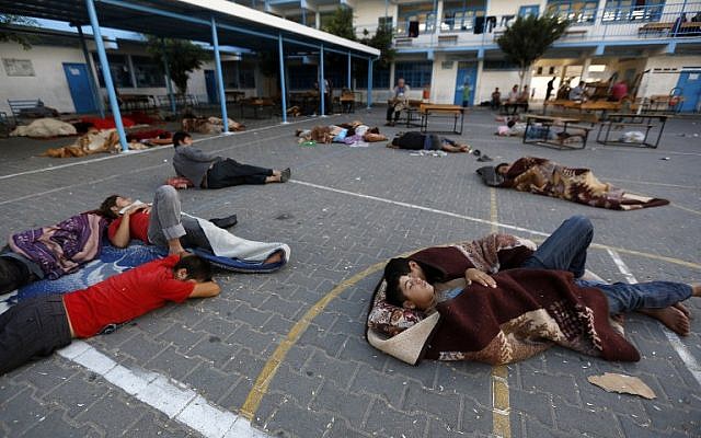 Palestinians sleep in the yard of a UN school in the northern Gaza Strip town of Beit Lahiya early on July 16, 2014, after evacuating their houses near the border with Israel. (photo credit: AFP/MOHAMMED ABED) Palestinians sleep in the yard of a UN school in the northern Gaza Strip town of Beit Lahiya early on July 16, 2014, after evacuating their houses near the border with Israel. (photo credit: AFP/MOHAMMED ABED)