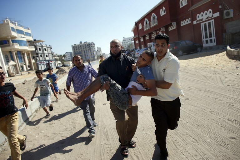 Palestinian employees of Gaza City's al-Deira hotel carry a wounded boy following an Israeli military strike near on the beach, on July 16, 2014. Four children were killed in Gaza City during the attack. (photo credit: AFP/THOMAS COEX) Palestinian employees of Gaza City's al-Deira hotel carry a wounded boy following an Israeli military strike near on the beach, on July 16, 2014. Four children were killed in Gaza City during the attack. (photo credit: AFP/THOMAS COEX)