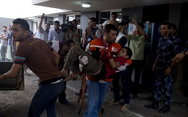 An injured Palestinian boy is carried into at Shifa hospital in Gaza City on Sunday, July 20, 2014 (photo credit: AFP/MAHMUD HAMS)