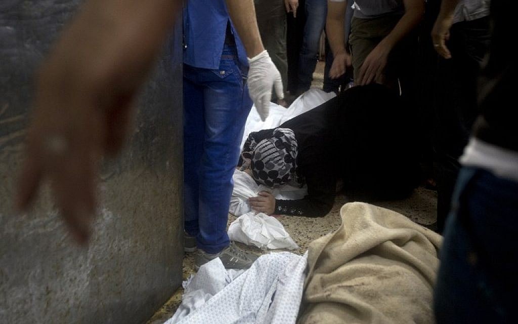 A woman grieves over a body lying on the ground of the morgue of the al-Shifa hospital in Gaza City, on July 20, 2014. (photo credit: AFP/MAHMUD HAMS)