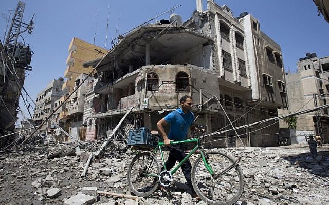 A Palestinian man pushes his bicycle amidst debris following an Israeli military strike in Gaza city, on July 23, 2014. (photo credit: AFP/ MAHMUD HAMS) A Palestinian man pushes his bicycle amidst debris following an Israeli military strike in Gaza city, on July 23, 2014. (photo credit: AFP/ MAHMUD HAMS)