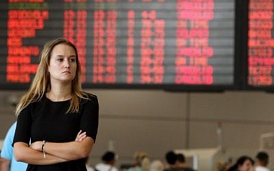 A traveler stands in front of a departure time flight board displaying various cancellations at Ben Gurion Airport on Wednesday, July 23, 2014. (photo credit: Gil Cohen-Magen/AFP)