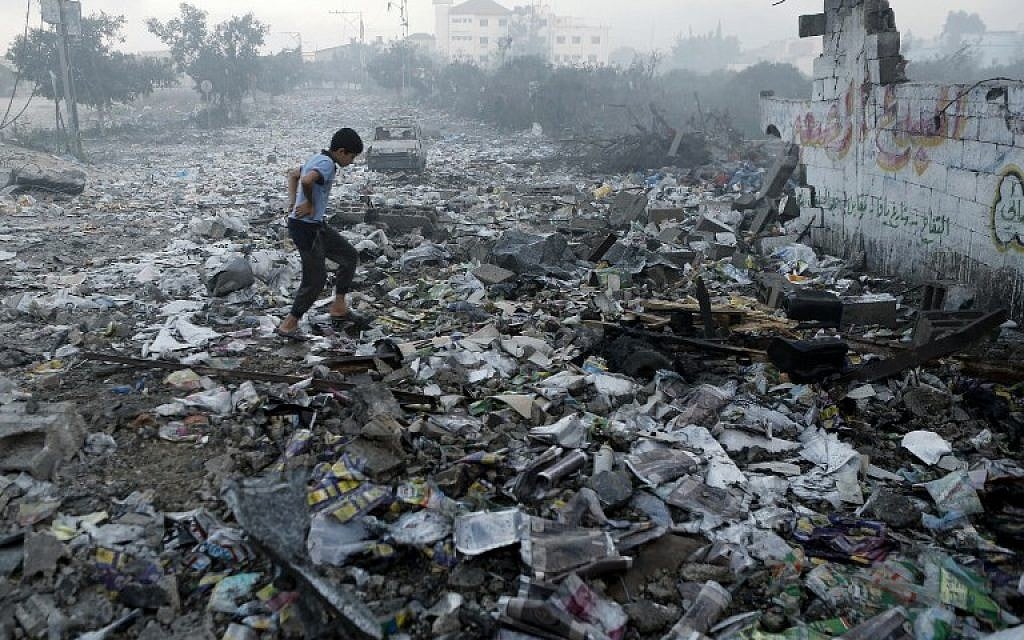 A Palestinian youth walks on debris as he inspects damages following an Israeli air strike in Gaza City, on July 24, 2014 (photo credit: AFP/MOHAMMED ABED)
