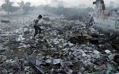 A Palestinian youth walks on debris as he inspects damages following an Israeli air strike in Gaza City, on July 24, 2014 (photo credit: AFP/MOHAMMED ABED)