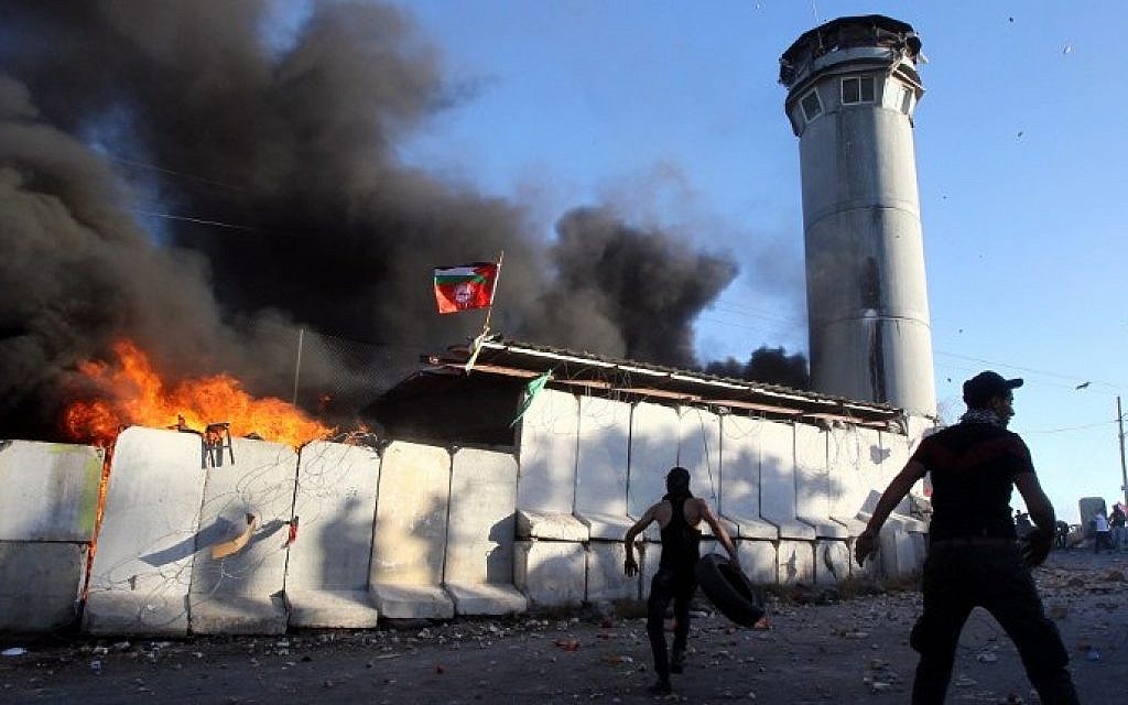 Palestinian protesters throw rocks and fireworks at an Israeli guard tower on July 25, 2014, in the Beit Ummar village, north of the West Bank city of Hebron (Photo credit: Hazem Bader/AFP)