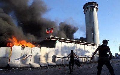 Palestinian protesters throw rocks and fireworks at an Israeli guard tower on July 25, 2014, in the Beit Ummar village, north of the West Bank city of Hebron (Photo credit: Hazem Bader/AFP)