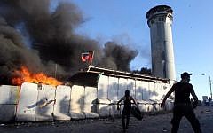 Palestinian protesters throw rocks and Molotov cocktails at an Israeli guard tower during the funeral of three men on July 25, 2014, in the Beit Omar village, north of the West Bank city of Hebron. (photo credit: Hazem Bader/AFP)