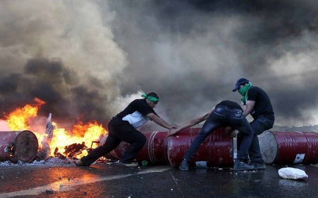 Palestinian protesters block Route 60, the main road between settlements in the West Bank, on Friday, July 25, 2014, in the village of Beit Omar, north the West Bank city of Hebron. (photo credit: Hazem Bader/AFP)