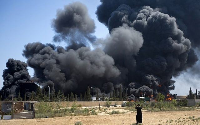 A Palestinian man looks on as flames engulf the fuel tanks of the only power plant supplying electricity to the Gaza Strip after it was hit on July 29, 2014,  (photo credit: AFP/MAHMUD HAMS)