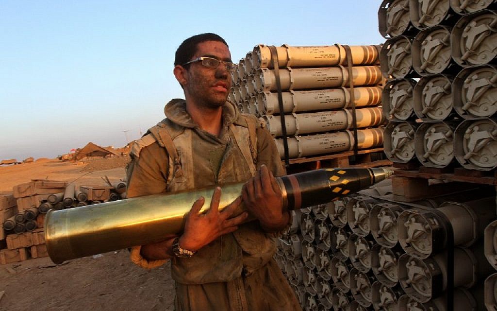 An Israeli soldier carries a shell as troops prepare munitions along the border between Israel and the Hamas-controlled Gaza Strip on July 30, 2014.  (photo credit: AFP/GIL COHEN-MAGEN)