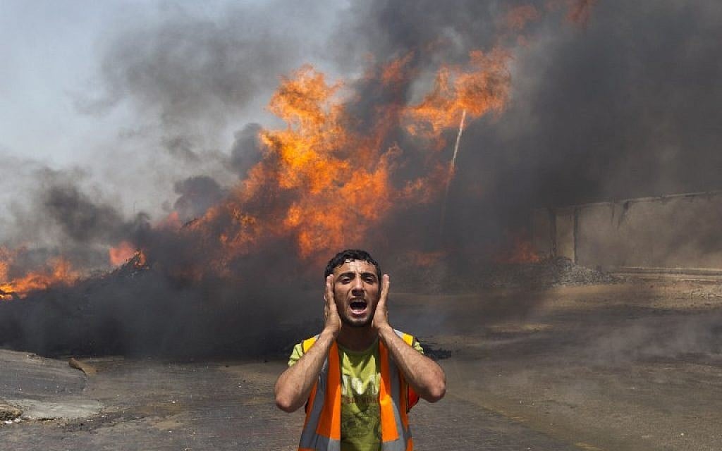 Palestinian firefighters try to extinguish fire at UN storehouse after an Israeli military strike in an area west of Gaza City on July 12, 2014. (photo credit: AFP/Mahmud Hams)