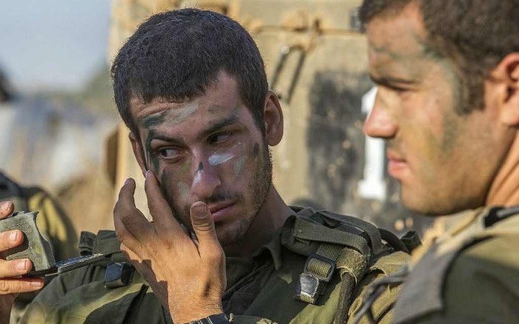 Israeli soldiers camouflage their faces at an army staging area along Israel's border with the Gaza Strip on July 30, 2014 (photo credit: AFP/JACK GUEZ)