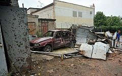 Local residents stand near a car destroyed after clashes between Ukrainian forces and pro-Russia militants in the eastern Ukrainian city of Lugansk on July 19, 2014. (photo credit: AFP/Alex Inoy)
