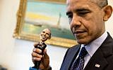 President Barack Obama holds a bobblehead doll of himself in the Outer Oval Office, May 14, 2014. (photo credit: White House/ Pete Souza)