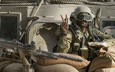 An illustrative photo of an Israeli soldier flashing the "V" for victory sign from an armored personnel carrier (APC) at an army deployment area near Israel's border with the Gaza Strip on July 17, 2014 (photo credit: AFP/ Jack Guez)