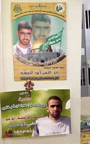 Amer Abu Ayshas certificate of health hangs on the family wall beneath a poster of his brother, Zaid, killed in 2005 (photo credit: Elhanan Miller/Times of Israel)