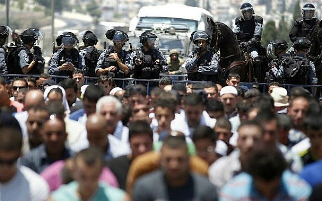 Israeli police stand guard as Muslim men pray in the middle of a street outside the Old City in East Jerusalem on July 4, 2014, during the first Friday prayer of the holy fasting month of Ramadan (photo credit: AFP/ Thomas Coex)