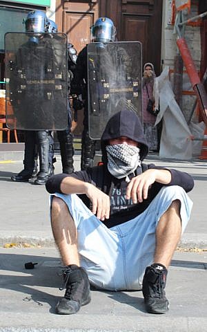 A pro-Palestinian protestor rests on a Parisian sidewalk while riot police observe on Saturday, July 26, 2014. (Glenn Cloarec/The Times of Israel)