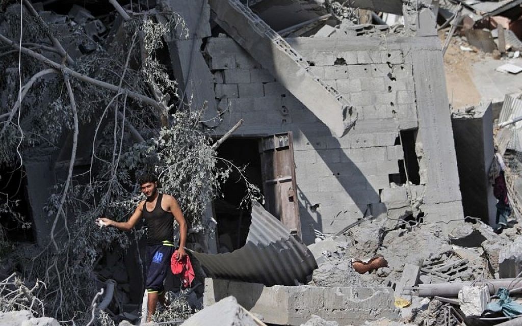 A Palestinian shows his pet bird which he managed to catch amid the rubble of houses destroyed by Israeli strikes in Beit Hanoun, northern Gaza Strip, Sunday, July 27, 2014. (Photo credit:AP/Lefteris Pitarakis)