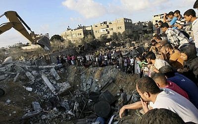 Palestinians gather around the rubble of a building on Saturday July 26, where at least 20 members of the Al Najar extended family were reported killed by an Israeli strike in Khan Younis, in the southern Gaza Strip. (photo credit:AP/Eyad Baba)