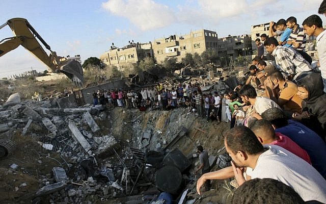 Palestinians gather around the rubble of a building on Saturday July 26, where at least 20 members of the Al Najar extended family were reported killed by an Israeli strike in Khan Younis, in the southern Gaza Strip. (photo credit:AP/Eyad Baba)