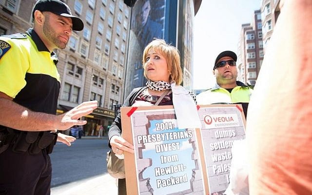 A Boston police officer tells a pro-Palestinian protester outside the Israeli consulate to "calm down" on Friday. Several Israel activists claimed this protester and others initiated physical contact with them, including knocking phones out of their hands, yanking on Israeli flags, and shouting "Jesus killers" in their faces (photo credit: Elan Kawesch/The Times of Israel)