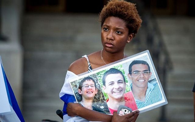 A Boston area student holds up photos of the three Israeli students who were murdered in the West Bank (photo credit: Elan Kawesch)