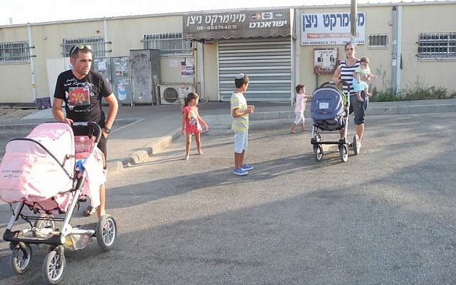 Deborah Israeli and Eviatar Cohen with their children outside the convenience store and grocer on Sunday, both of which were closed due to the situation. Deborah Israeli and Eviatar Cohen with their children outside the convenience store and grocer on Sunday, both of which were closed due to the situation. photo credit: Melanie Lidman/Times of Israel)