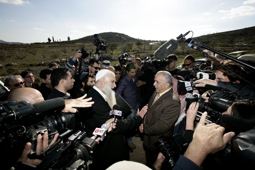 The late Rabbi Menachem Froman (L), a leader of the settler peace activist movement, meets with Palestinians at roadblock outside the West Bank village of Yasuf, in December 2009, to apologize for an act of vandalism in a village mosque (photo credit: Abir Sultan/Flash 90)