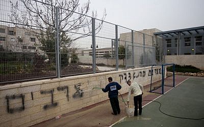 Workers clean off the Graffiti at the Jewish-Arab bilingual school in Jerusalem stating 'death to Arabs' and 'Kahana was right,' Feb 7, 2012 (photo credit: Flash90)